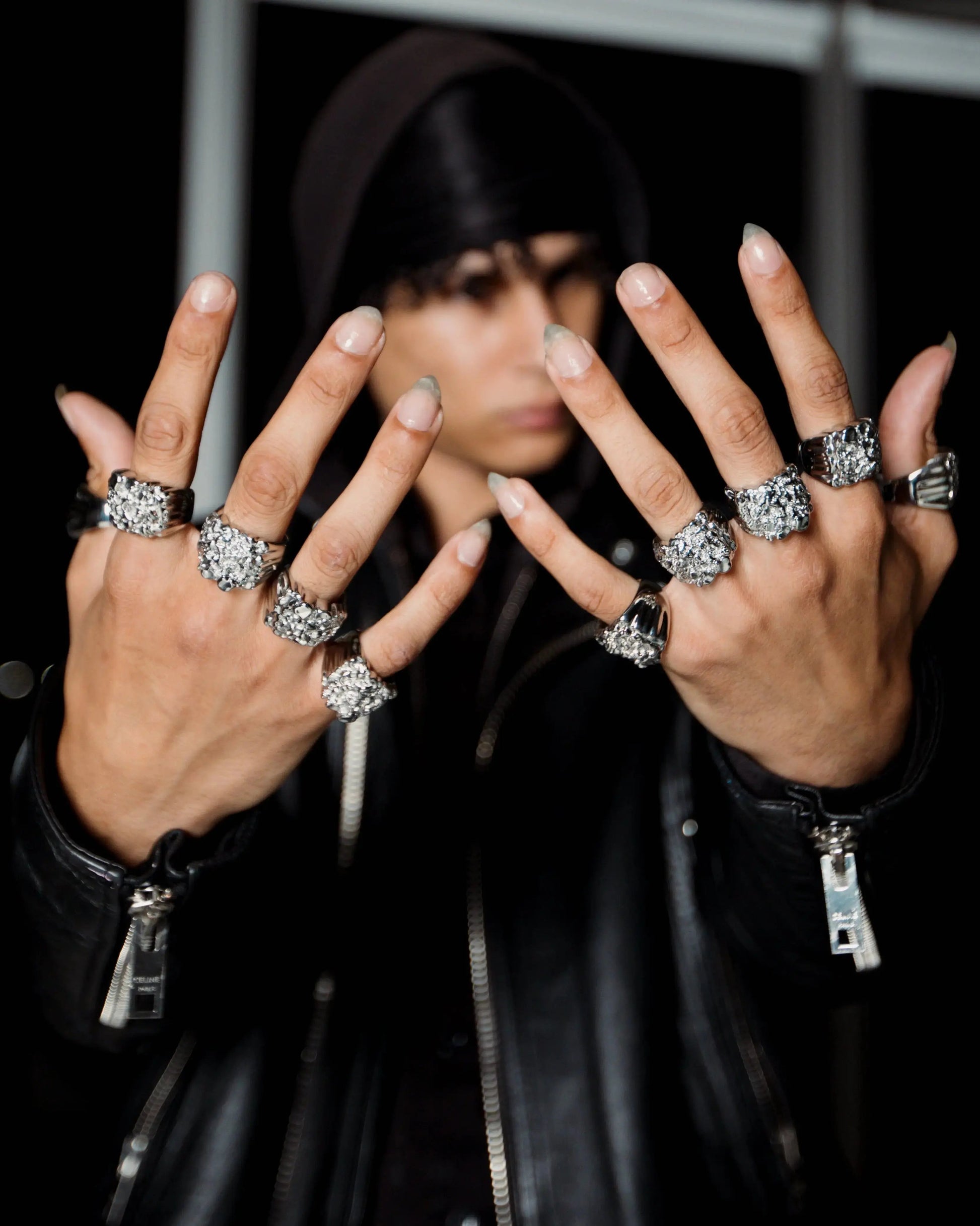 Person wearing multiple rings on fingers with a blurred background