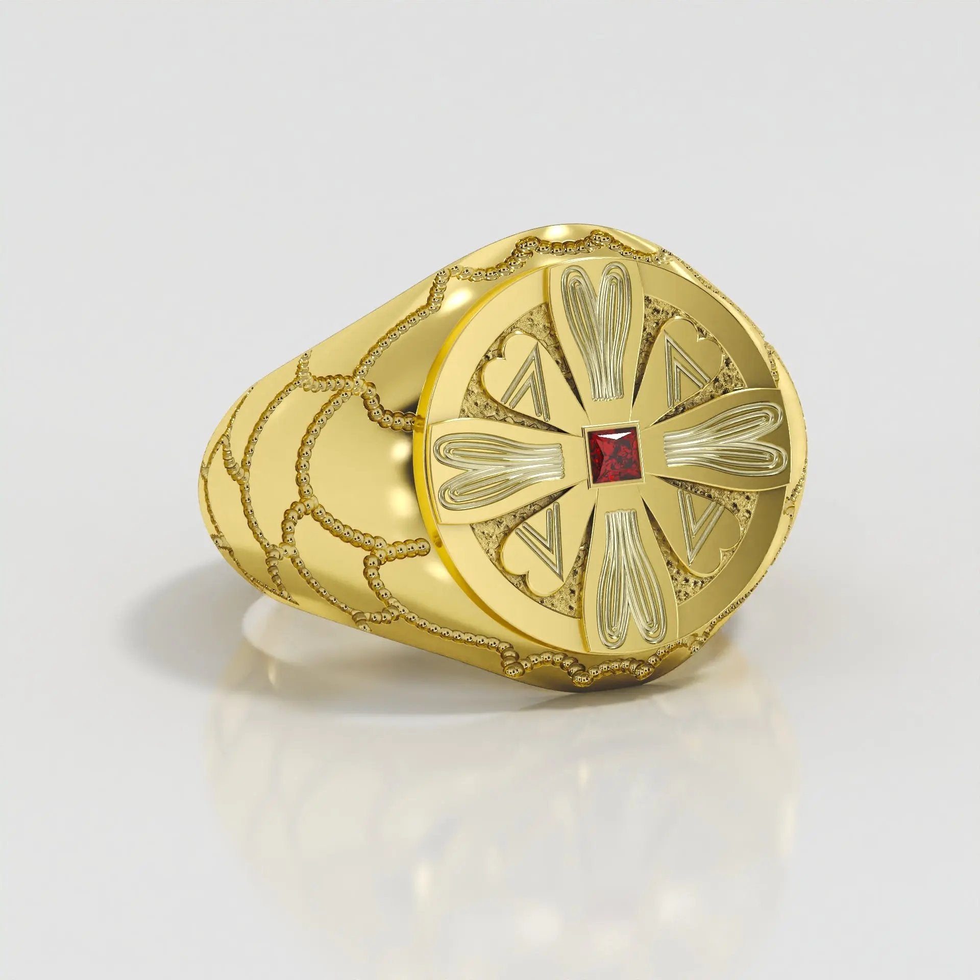 Gold ring with intricate design and a red zircon on a light gray background